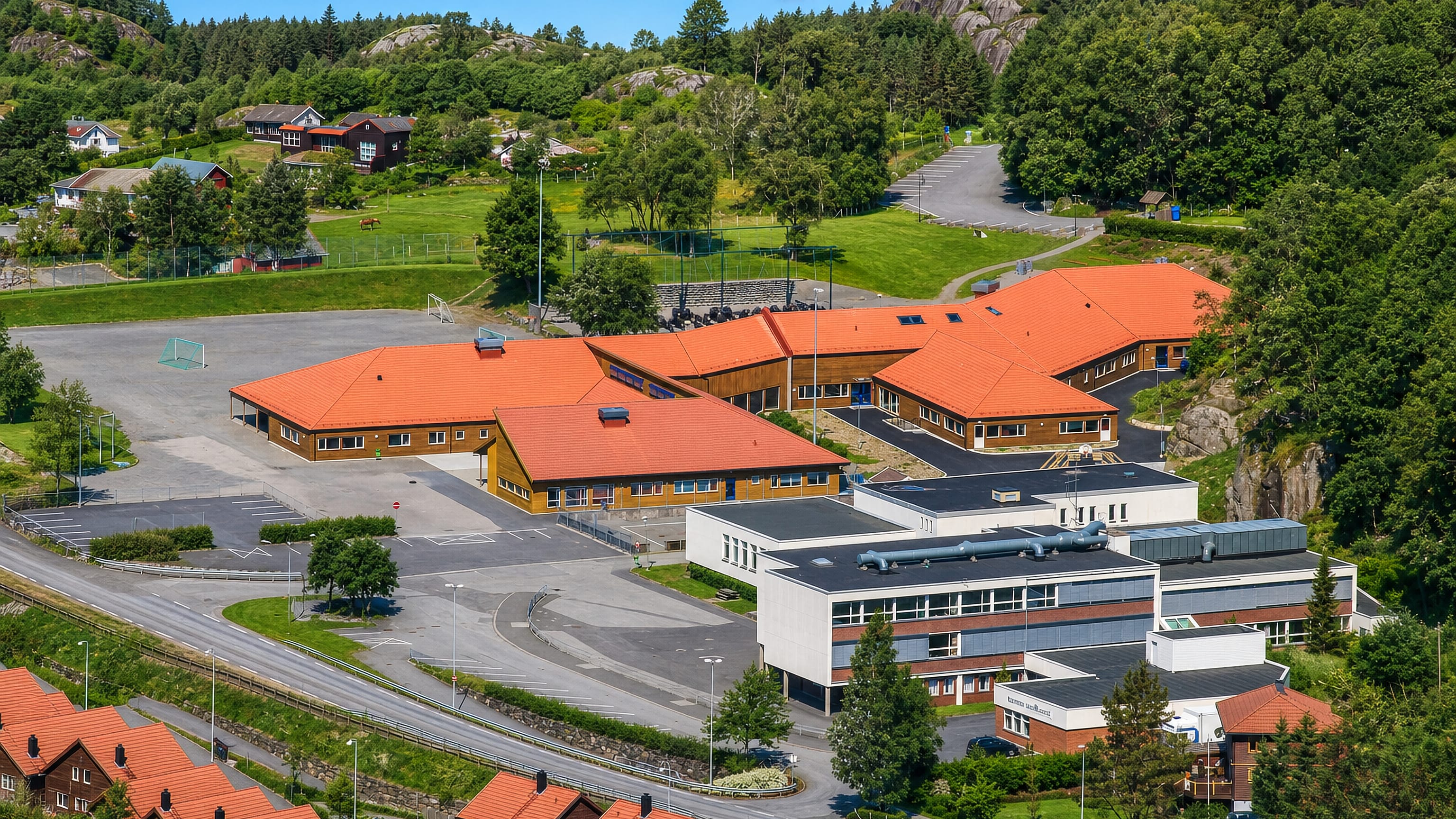 Red-roofed school and houses set among rocky wooded hills in Vikesa, Rogaland.