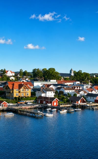 Langesund, Norway: white and red wooden houses and a hilltop church lining the boat-filled fjord waterfront.