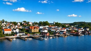 Langesund, Norway: white and red wooden houses and a hilltop church lining the boat-filled fjord waterfront.
