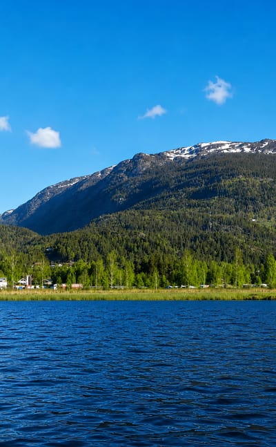 Forested mountains rising above the lake and a lakeside campsite at Seljord