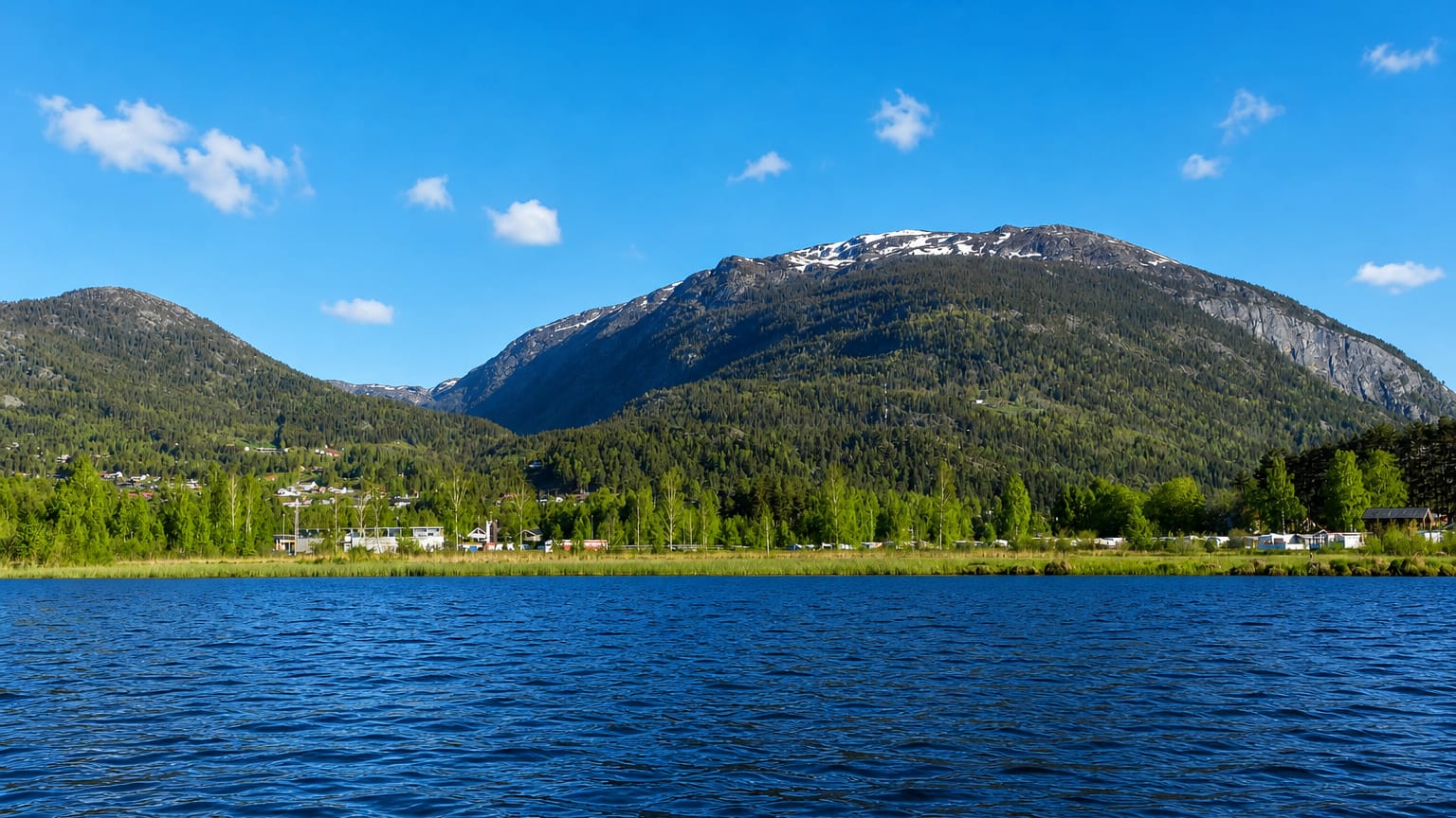 Forested mountains rising above the lake and a lakeside campsite at Seljord