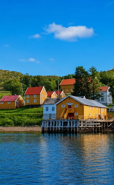 Traditional yellow, white and red wooden houses and waterside warehouses on stilts along the fjord at Hamnvik, Norway