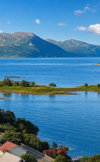 Fjord landscape near Harstad, Norway, with a flat-topped mountain, islets and a power-line pylon.
