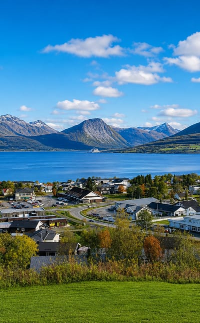 Storsteinnes, Norway, spread along a broad fjord beneath snow-flecked mountains in autumn.