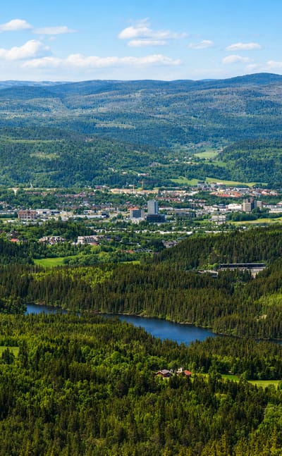 Aerial view of a town in a forested valley with a river winding through hills at Klaebu, Norway