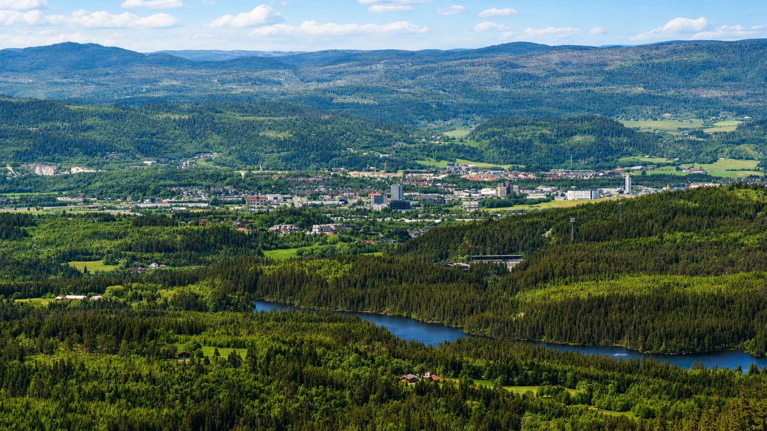Aerial view of a town in a forested valley with a river winding through hills at Klaebu, Norway