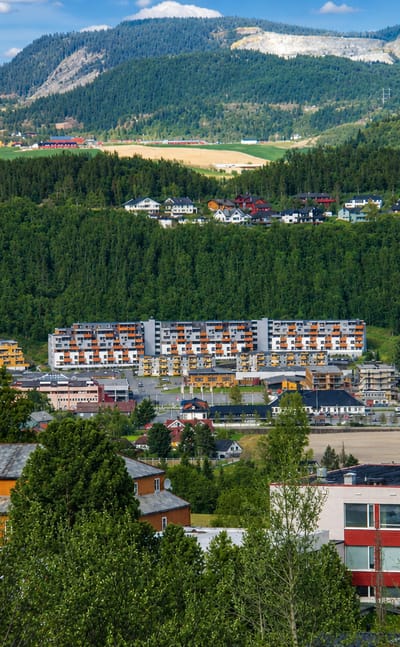 Melhus, Norway, a valley town of low-rise buildings and apartment blocks beneath forested hills and farmland.