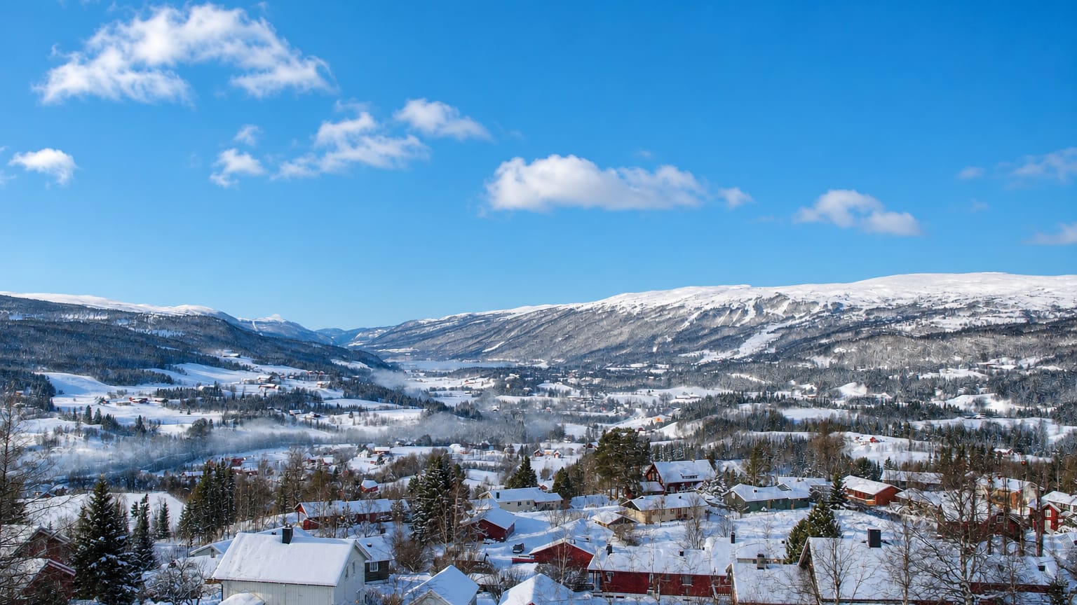 Snow-covered houses and forest in the mountain valley of Meråker, Trøndelag, Norway, under a blue winter sky