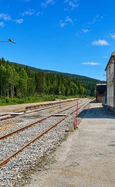Namsskogan railway station and platform beside forested hills in Namsskogan, Norway.
