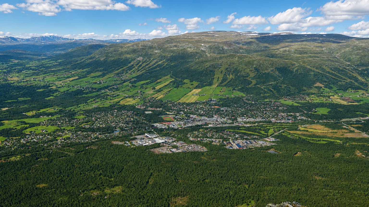 Aerial view of Oppdal town in its valley with ski slopes and surrounding mountains, Norway
