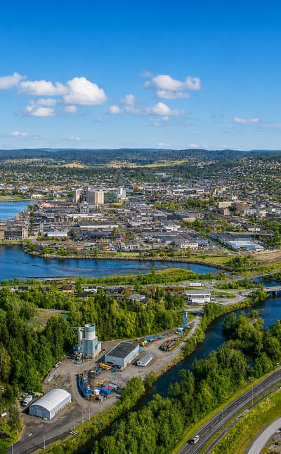 Aerial view of Steinkjer, Norway, its town centre at the river mouth on the fjord, with the winding river, highway and forested hills.
