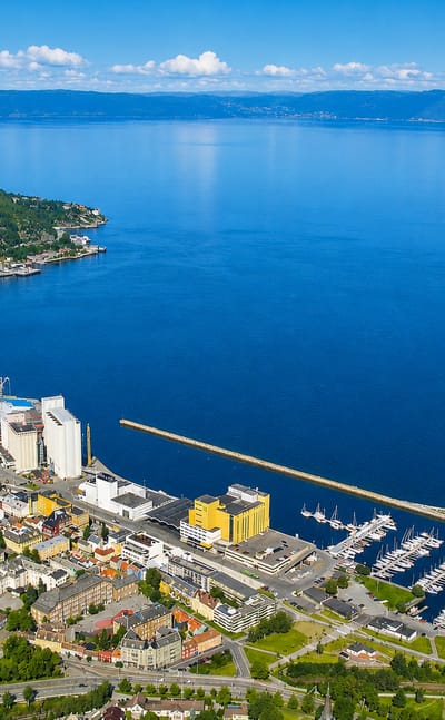 Aerial daytime view of Ila in Trondheim, Norway, with its harbour, marina and grain silos along the blue Trondheimsfjord.