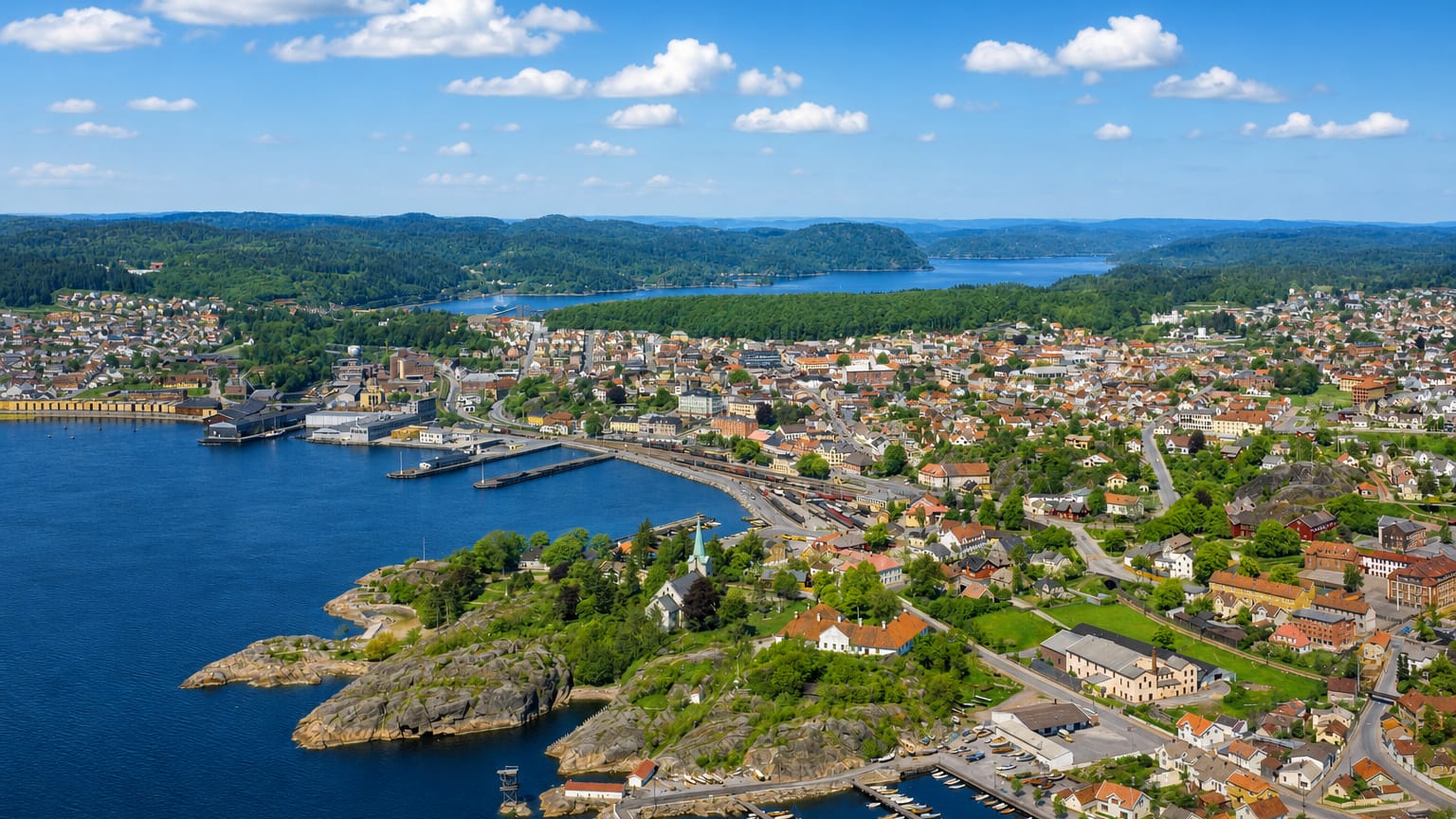 Aerial view of Larvik's harbour and town spread along the fjord with forested hills behind