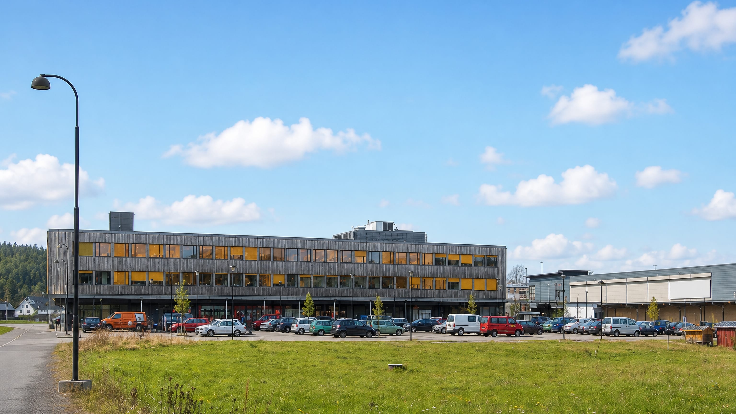 Timber-clad civic building and its car park at the centre of Revetal in Vestfold, Norway