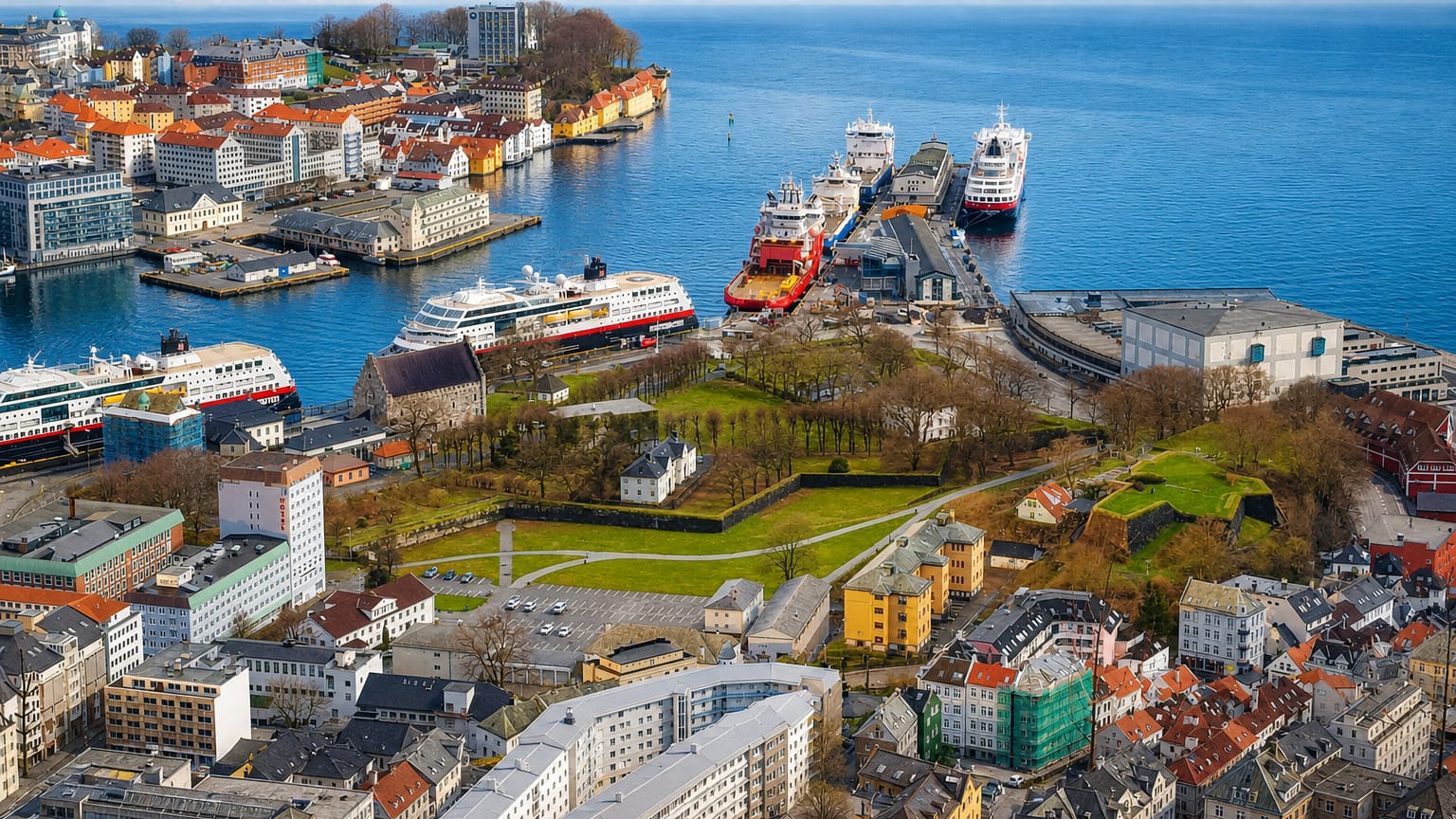 Aerial view of Bergenhus, Bergen — harbour with moored ships, green fortress grounds and colourful waterfront buildings.