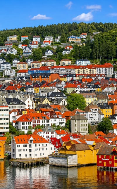 White and yellow waterfront warehouses below colorful wooden hillside houses in Skuteviken, Bergen, Norway