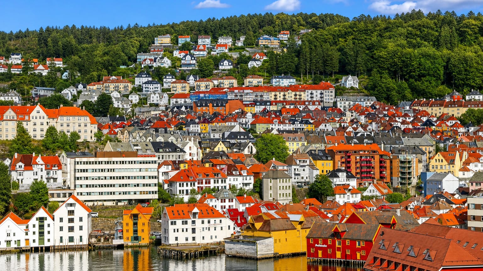 White and yellow waterfront warehouses below colorful wooden hillside houses in Skuteviken, Bergen, Norway
