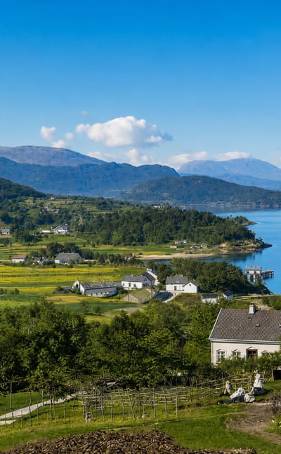 Dale in Fjaler, Norway: white farmhouses and turf-roofed cabin on green slopes above the blue Dalsfjorden and mountains