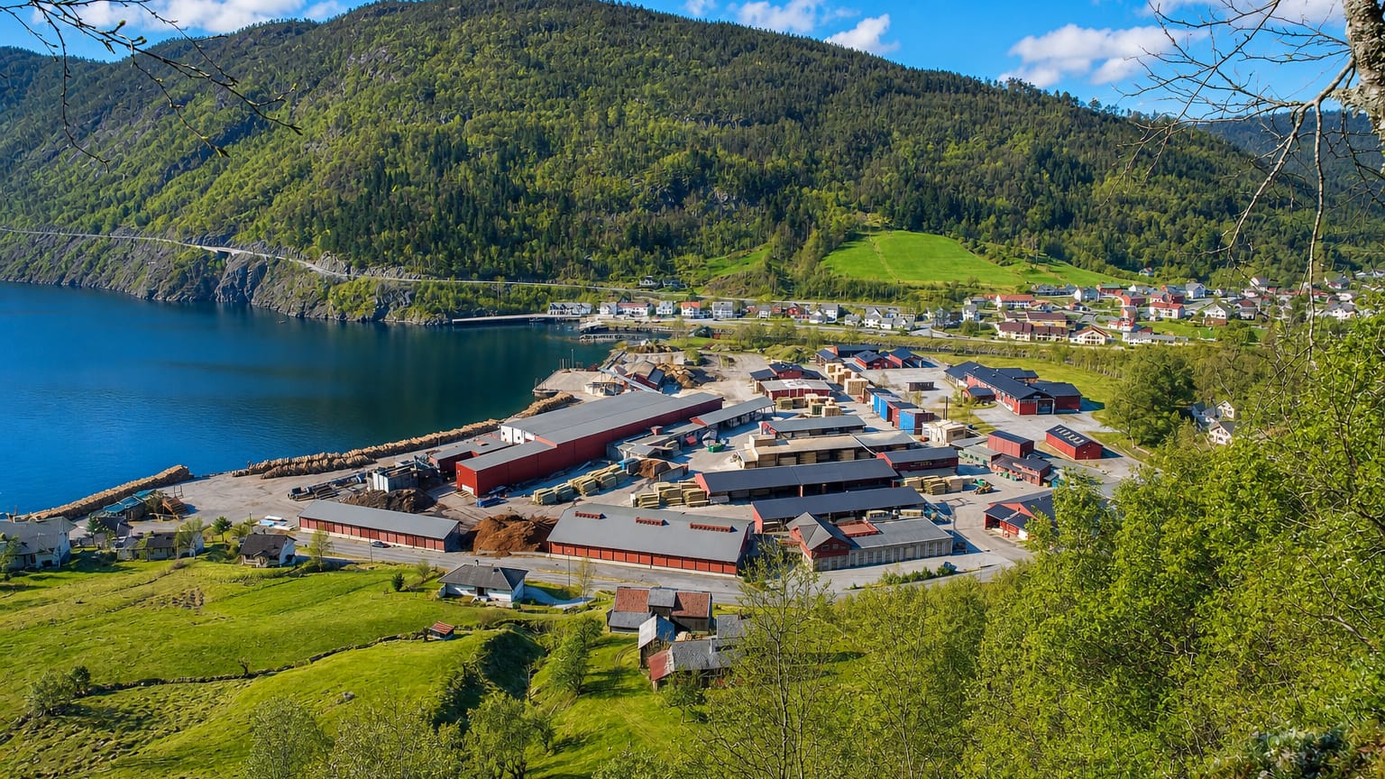 Granvin settlement at the head of the Granvinsfjord, with waterfront buildings below steep forested mountains and green farmland.