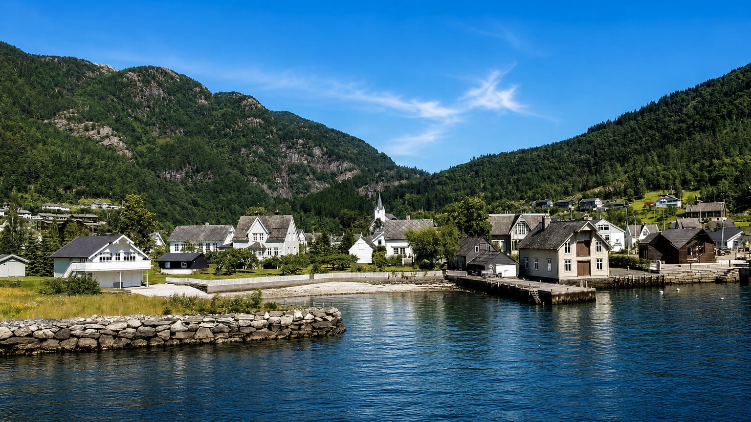 Jondal village on the Hardangerfjord, white wooden houses and a steepled church below forested mountains
