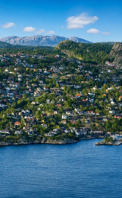Kleppestø's hillside of wooden houses above the fjord, with the ferry terminal at right and forested mountains beyond