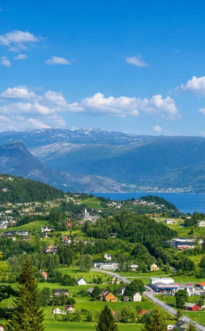 Village and lake set against the Hardangerfjord and snow-capped mountains at Norheimsund, Norway