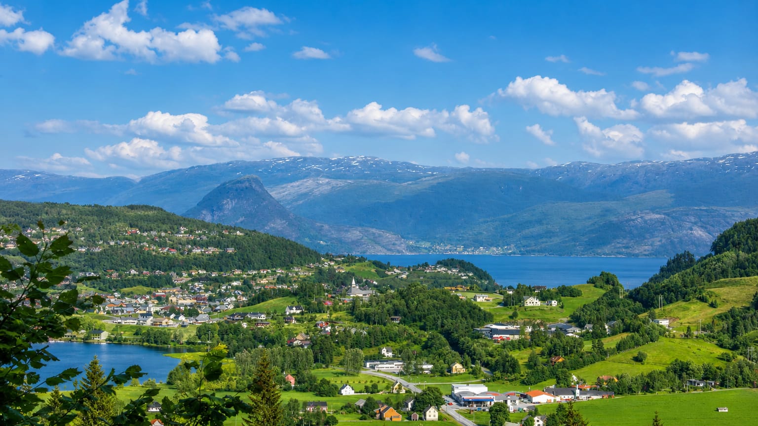 Village and lake set against the Hardangerfjord and snow-capped mountains at Norheimsund, Norway