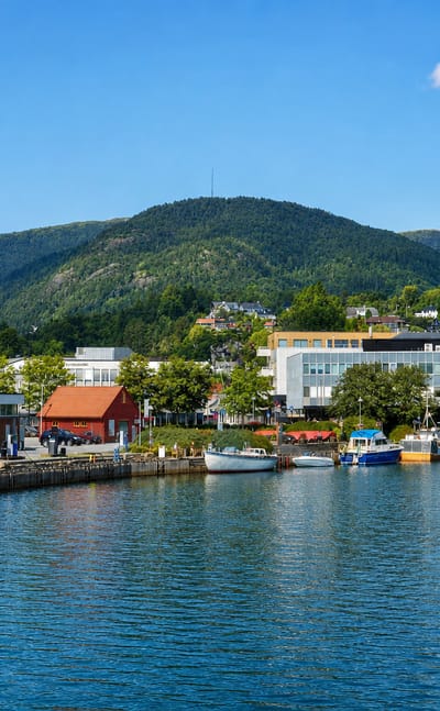 Boats moored along the harbour of Osoyro below a forested mountain, Norway