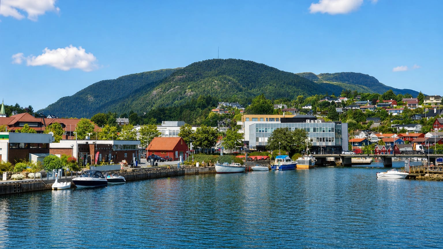 Boats moored along the harbour of Osoyro below a forested mountain, Norway