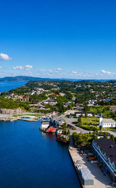 Aerial view of Storebo's harbour, white church and islet-dotted coast in Austevoll, Vestland, Norway.