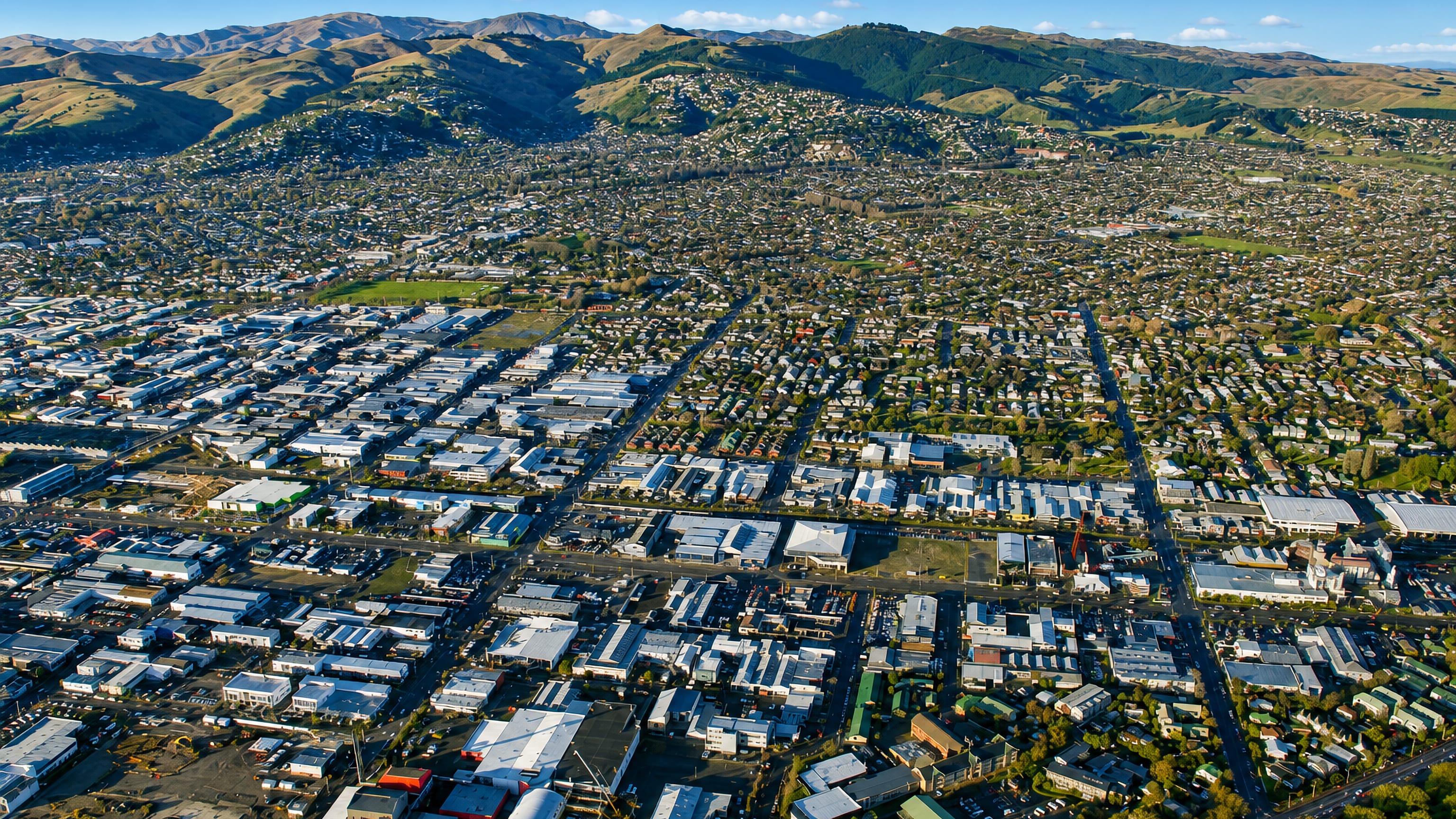 Aerial view over Sydenham's warehouses and grid streets in Christchurch, with the Port Hills beyond