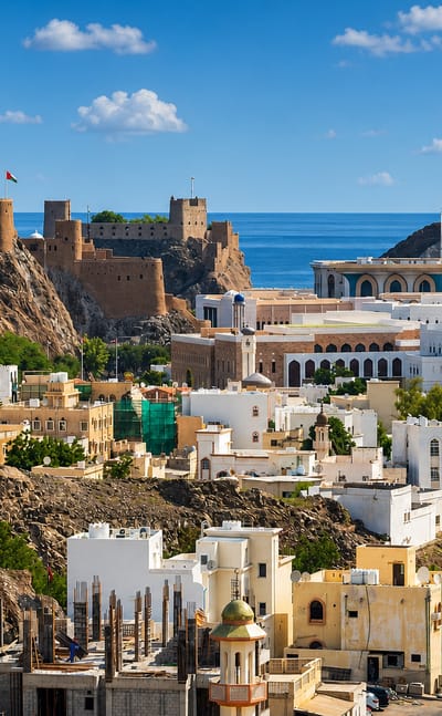 Old Muscat with hilltop Portuguese forts, white houses and mosque against rocky hills and sea