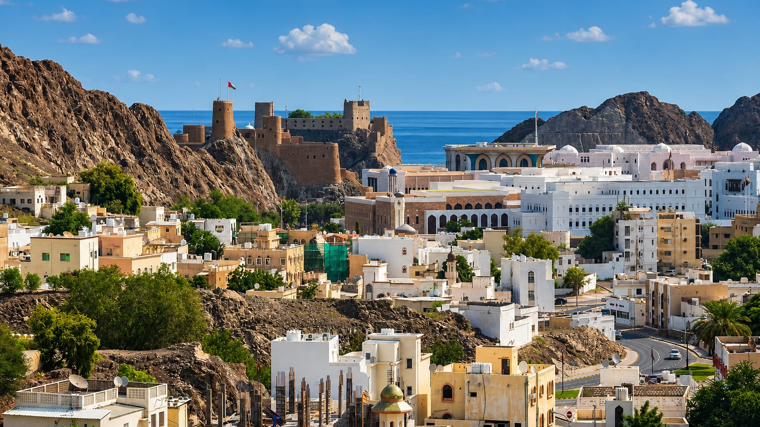 Old Muscat with hilltop Portuguese forts, white houses and mosque against rocky hills and sea
