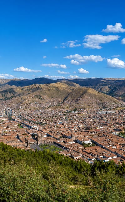 Cusco's red-tiled old town filling the Andean valley seen from a hillside, Peru