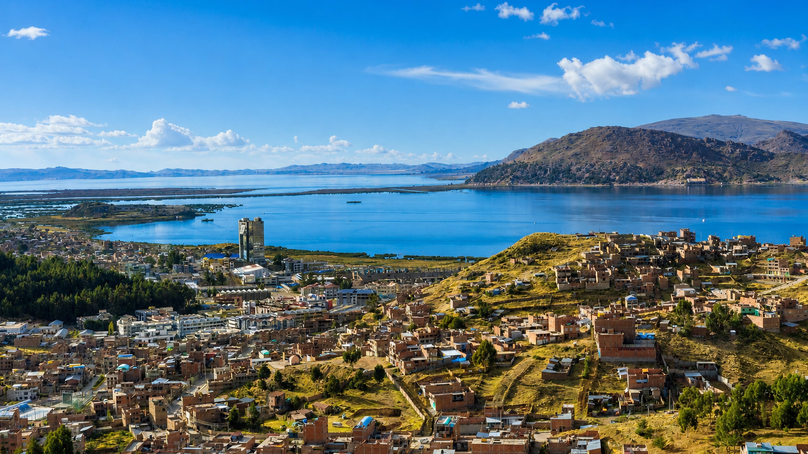 Puno, Peru spreading across hillsides above the blue bay of Lake Titicaca under a clear sky.