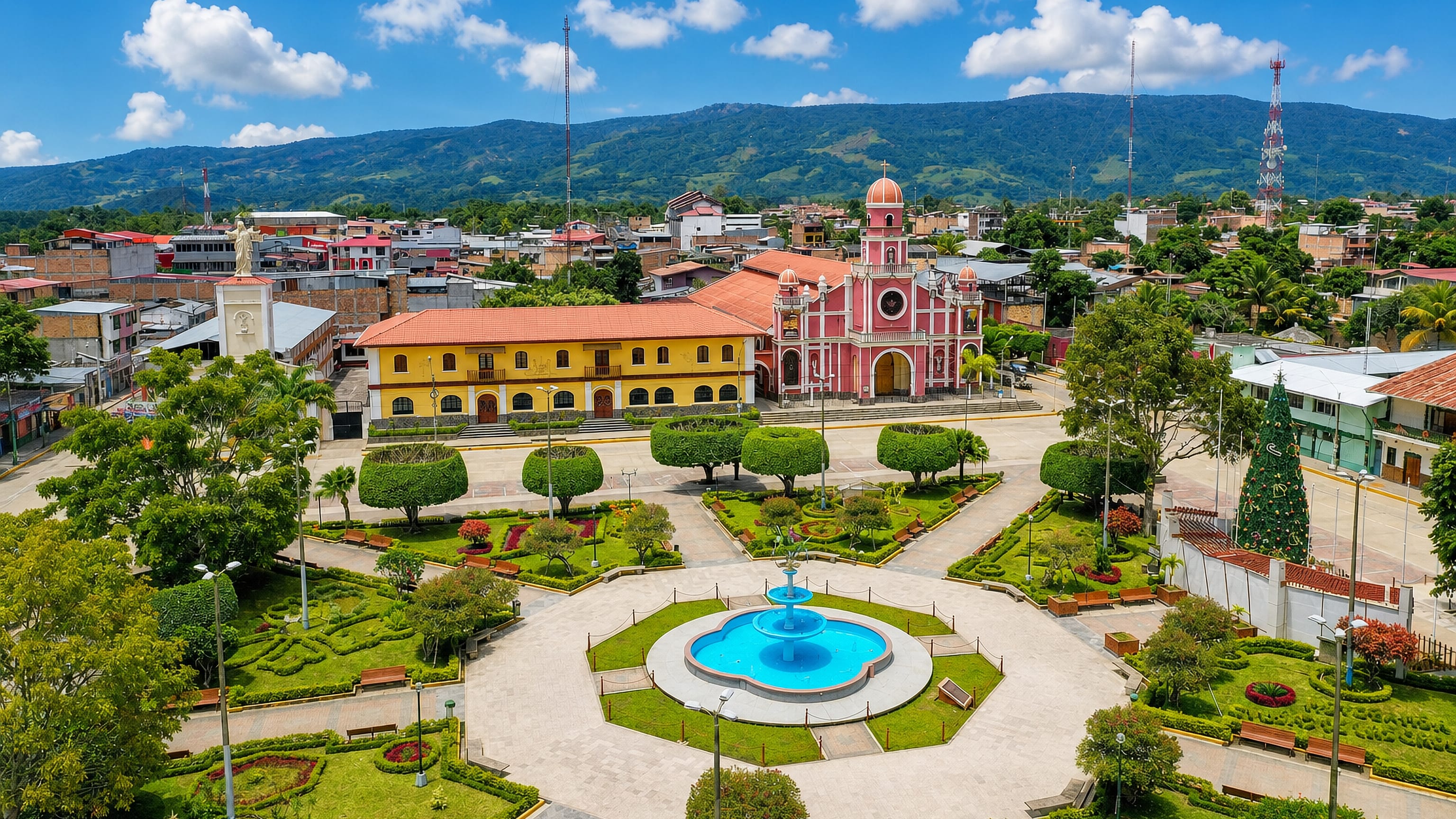 Moyobamba's Plaza de Armas in Peru's San Martin region, with fountain, pink church and jungle hills beyond.
