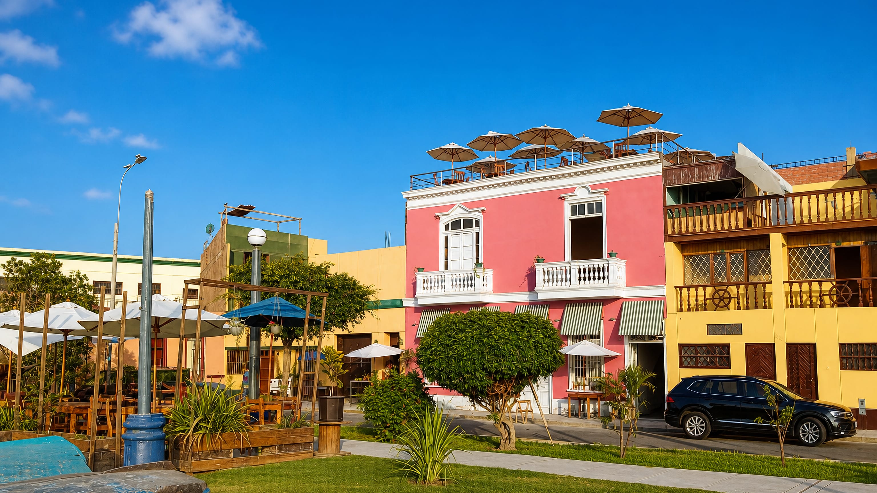 Pastel colonial houses with wooden balconies and rooftop terraces beside a lawn in Chucuito, Callao.