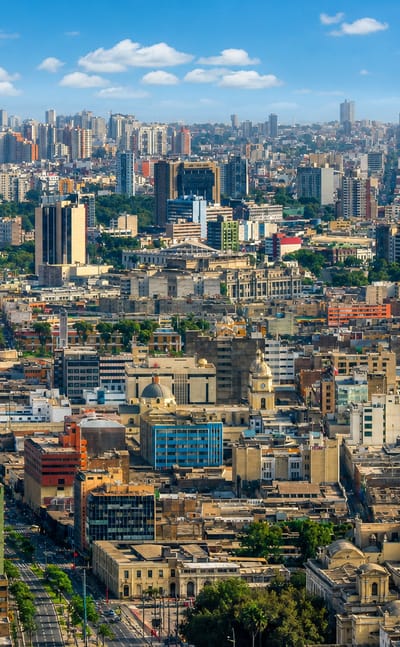 Dense daytime skyline of central Lima with high-rises and historic buildings under a blue sky