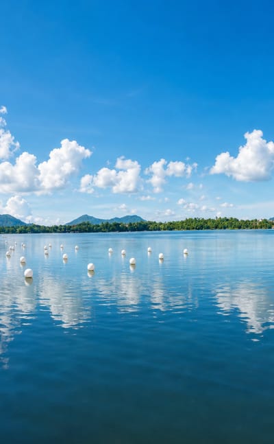 Sampaloc Lake at San Pablo, Philippines, ringed by a lakeside walkway with volcanic peaks on the horizon
