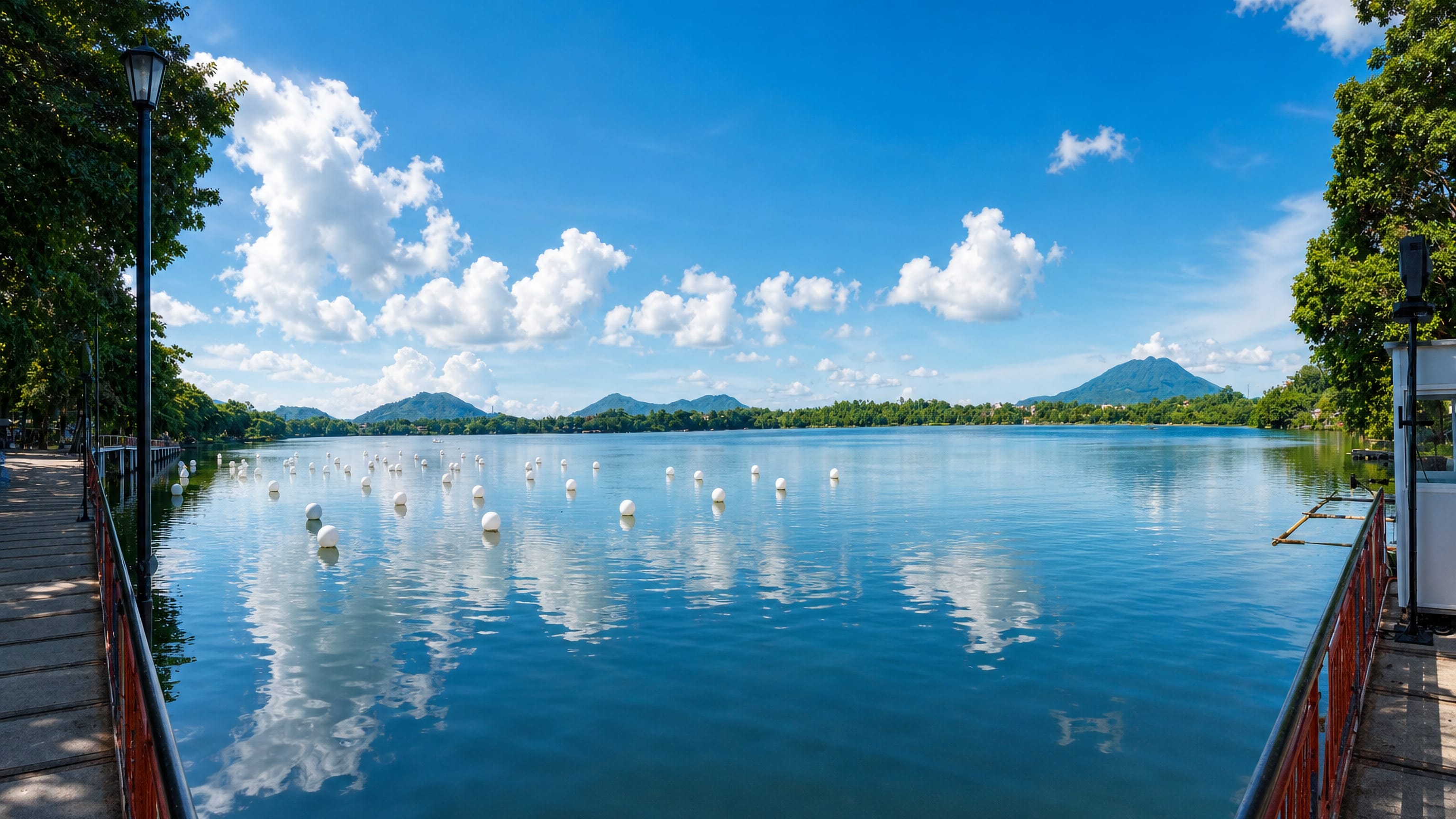 Sampaloc Lake at San Pablo, Philippines, ringed by a lakeside walkway with volcanic peaks on the horizon