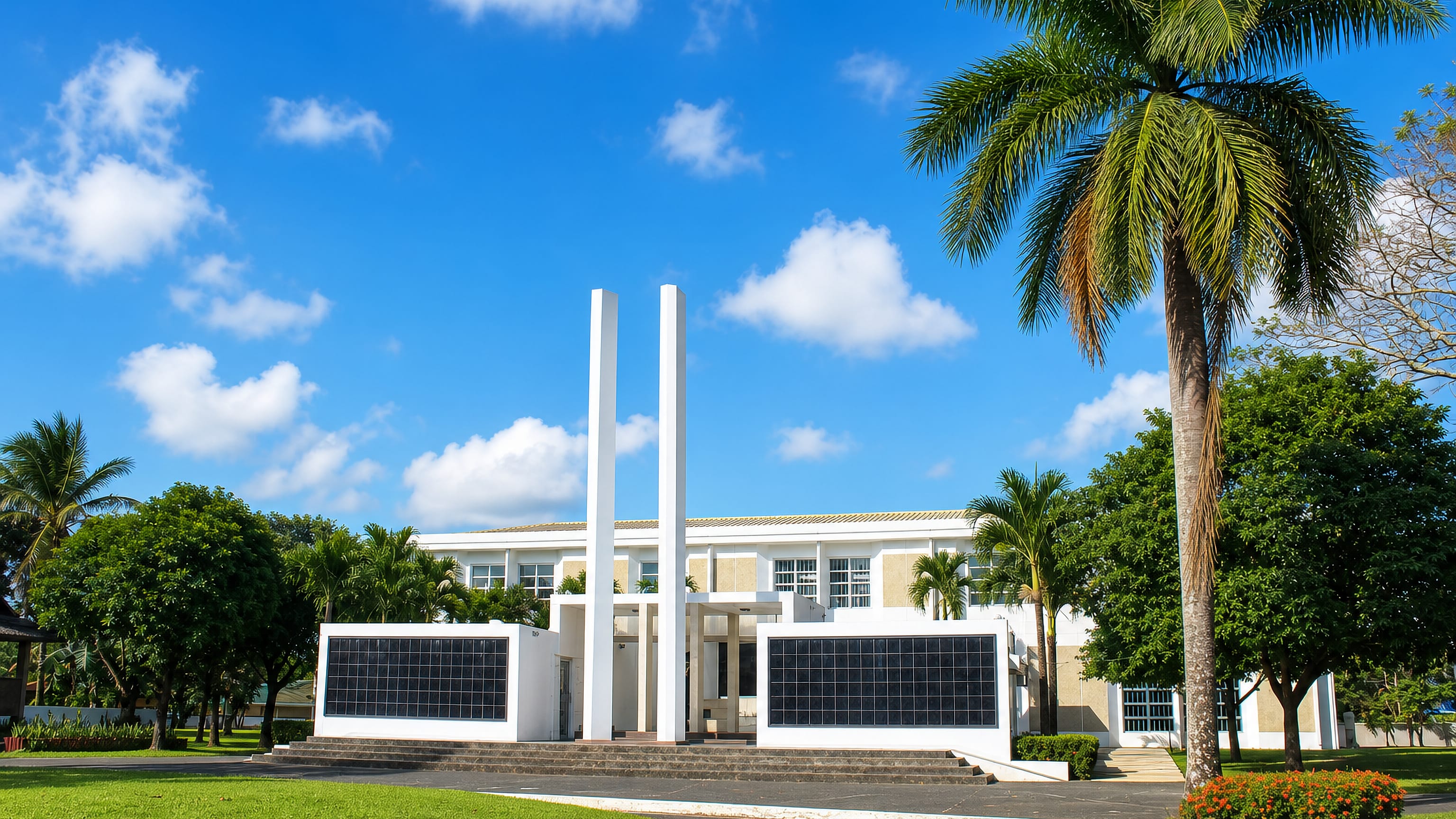 A white modernist civic building framed by palms and lawns in Tanauan, Batangas, Philippines.
