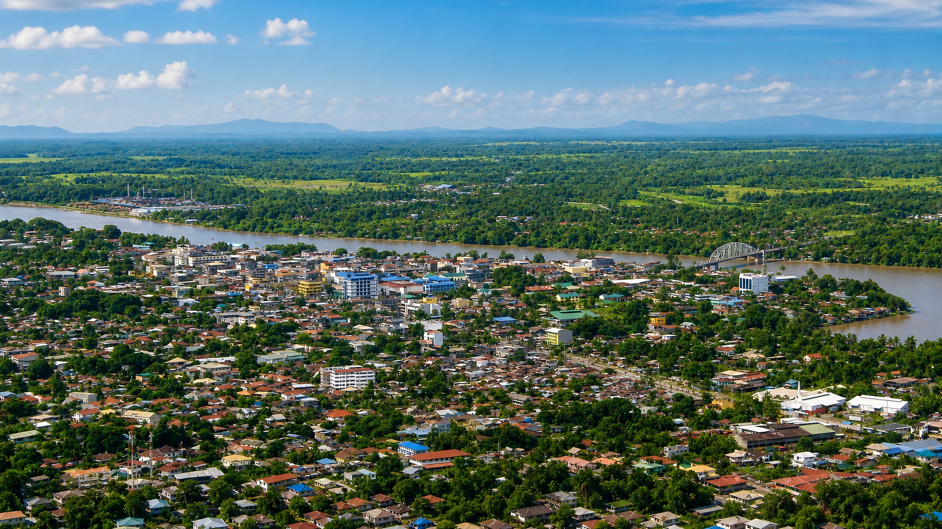 Butuan's low-rise sprawl along the Agusan River, with a steel truss bridge and green plains beyond.