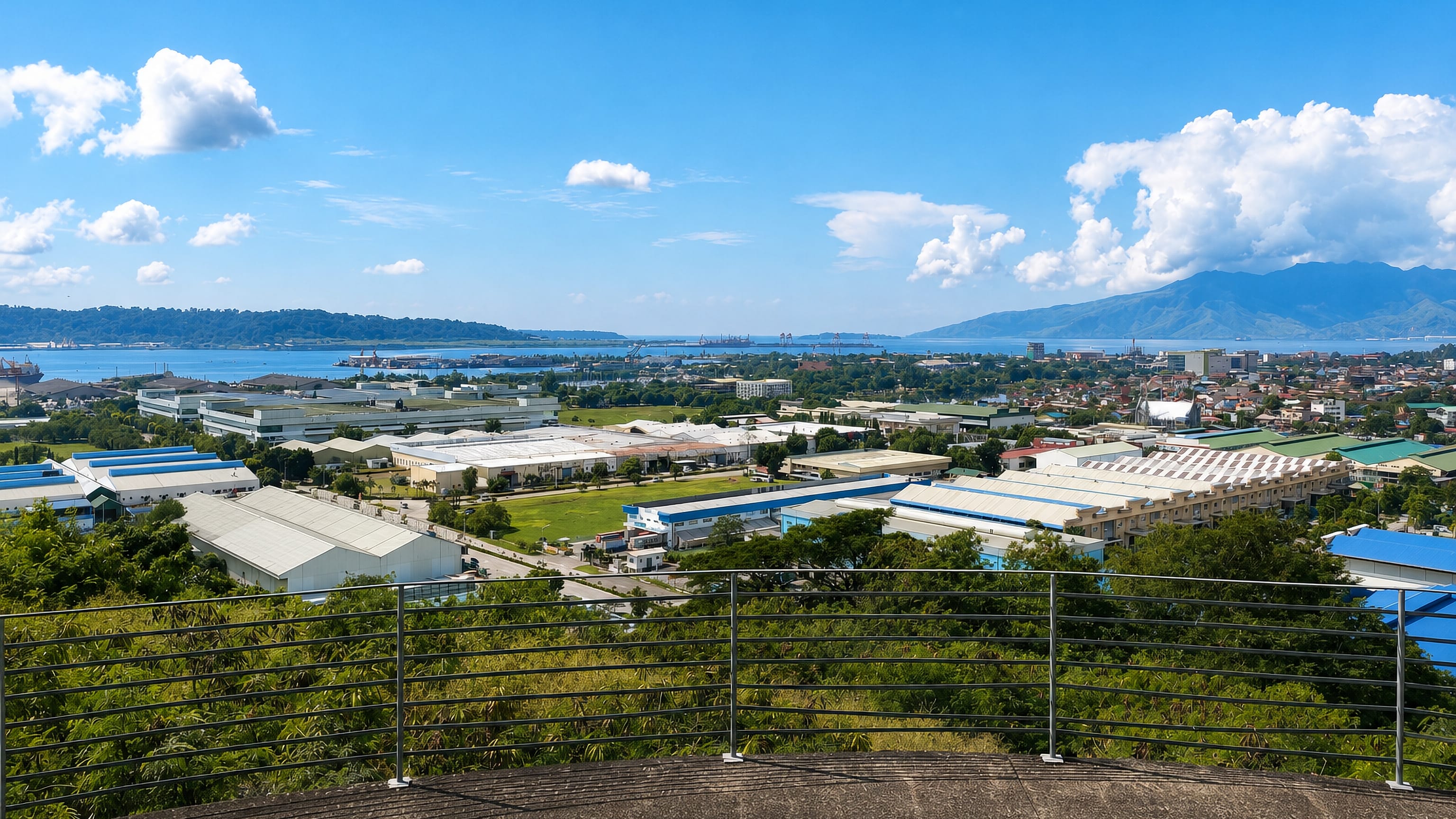 Hilltop overlook across Olongapo, Philippines, toward the Subic Bay freeport warehouses, port cranes and mountains.