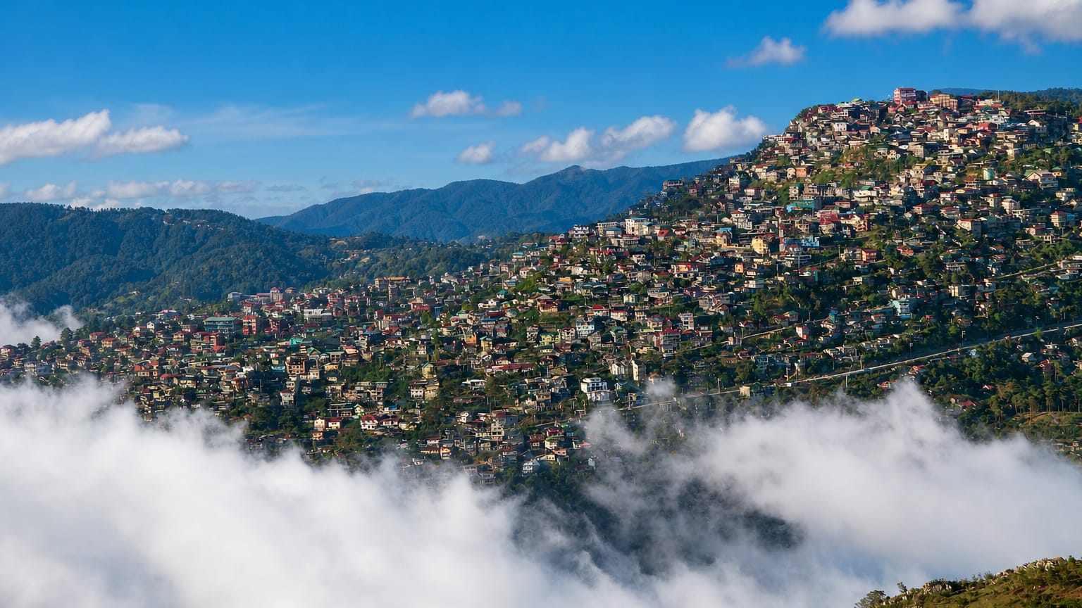 Colourful houses blanketing the pine-clad hillsides of Baguio, Philippines, above a sea of clouds.