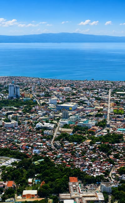 Aerial view of Davao City, Philippines, its downtown along Davao Gulf with the river and distant mountains.