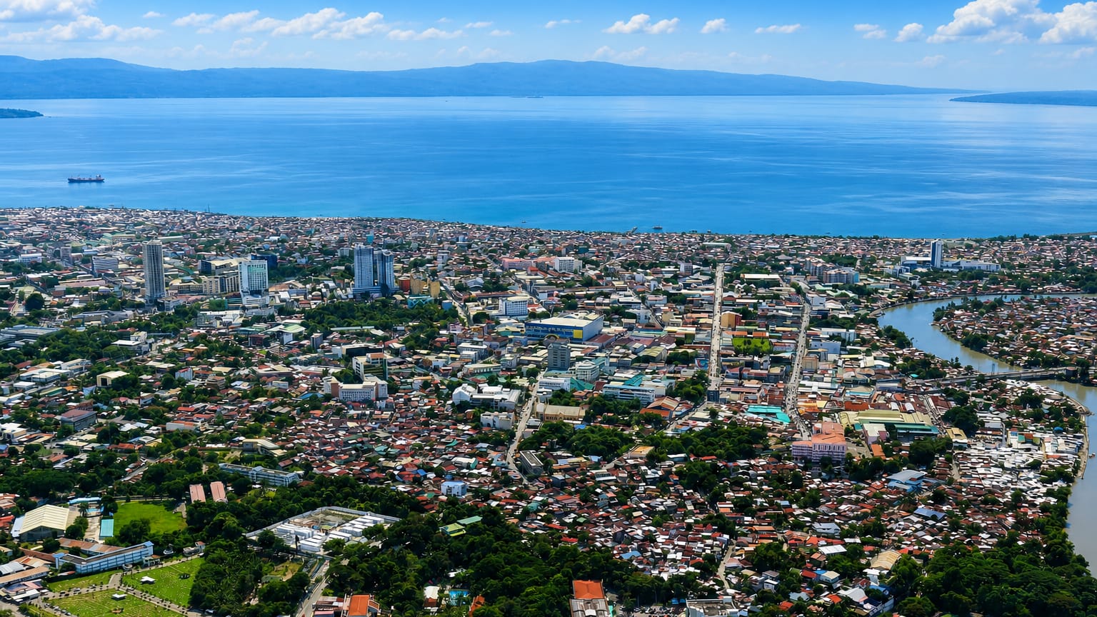 Aerial view of Davao City, Philippines, its downtown along Davao Gulf with the river and distant mountains.