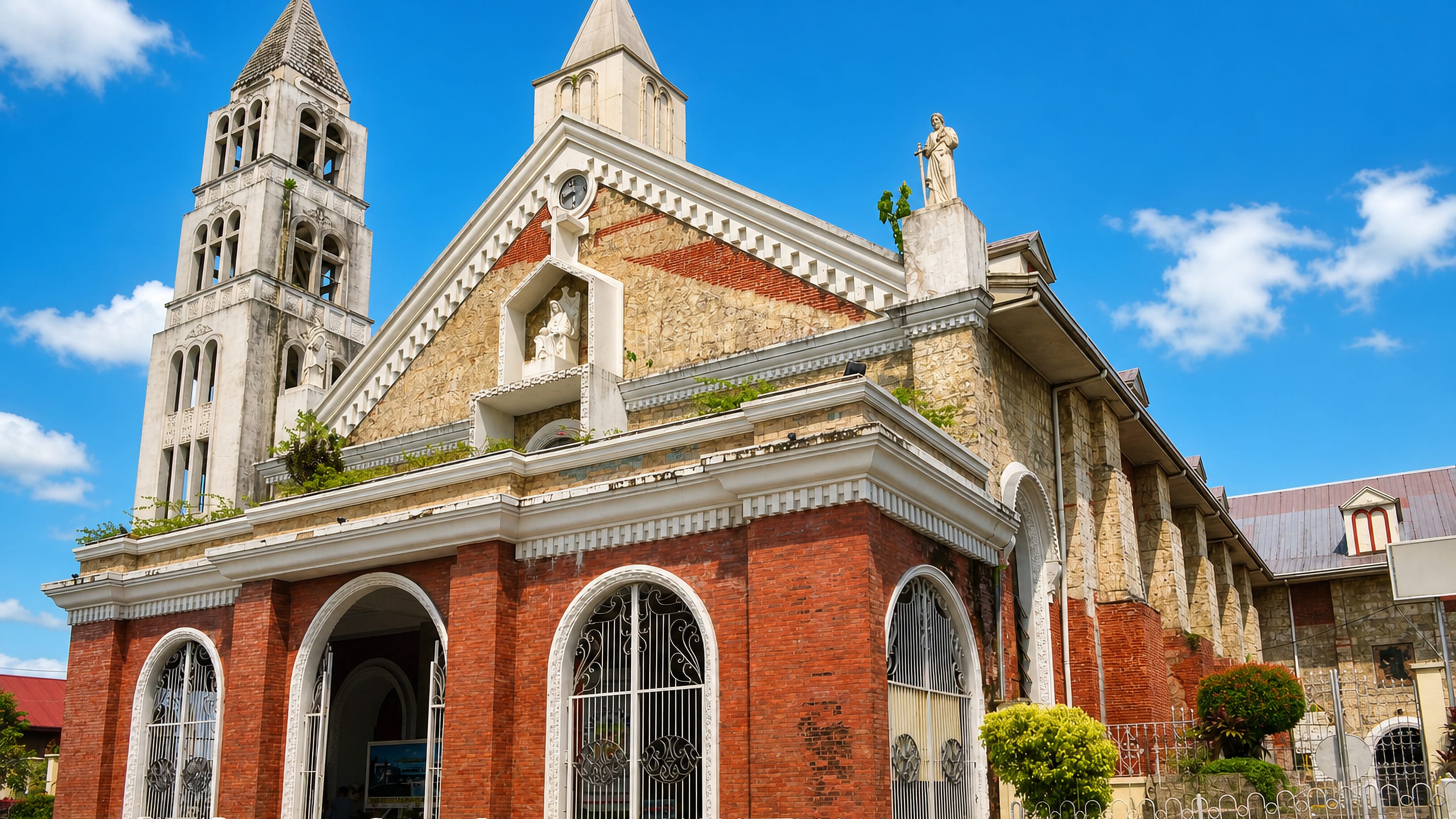 The brick-and-stone Calbayog Cathedral and its free-standing bell tower under a bright Samar sky.