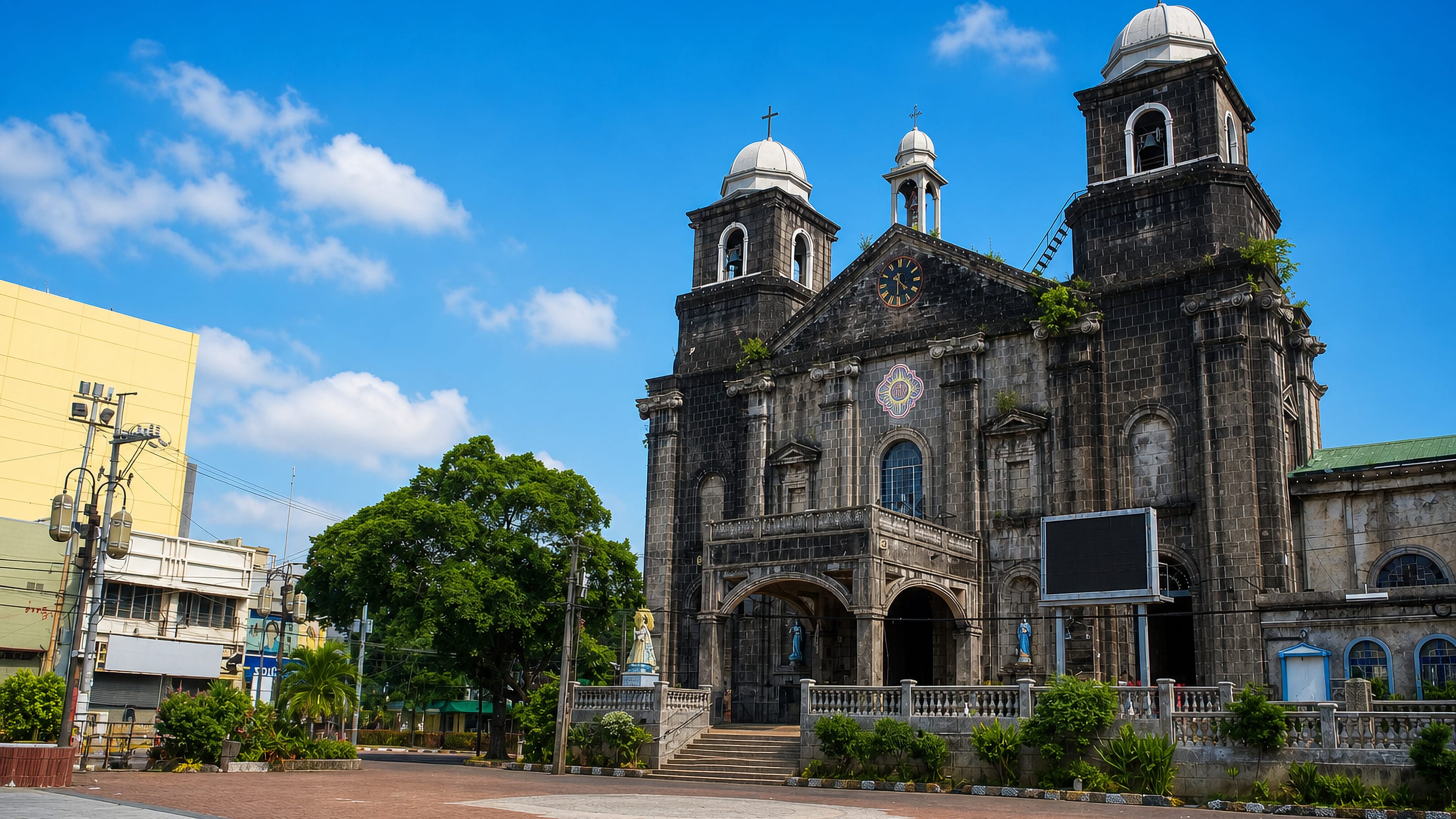 Stone twin-towered colonial church facing an open brick plaza in Tondo, Manila, under a bright blue sky.