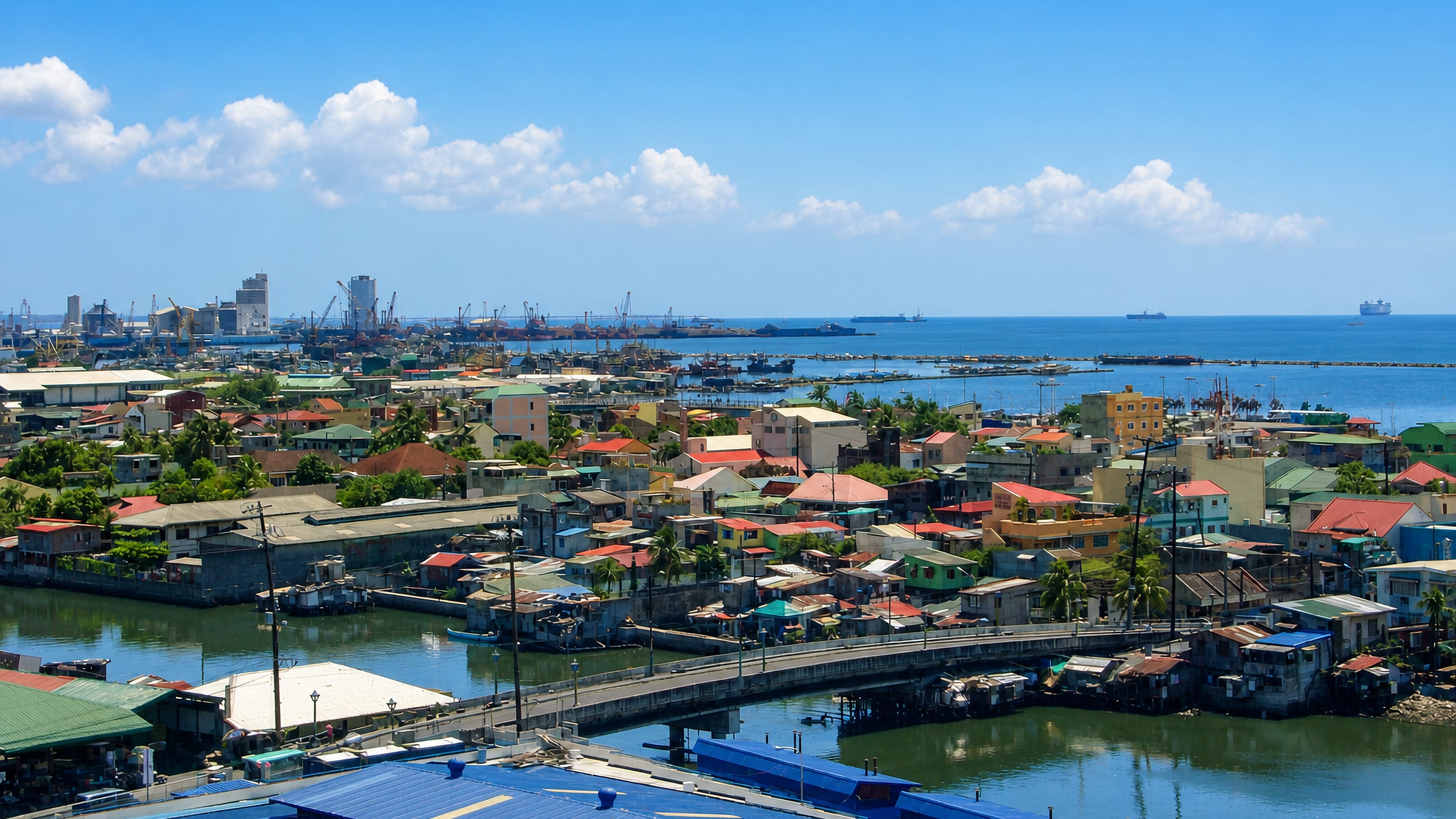 Navotas's dense fishing-port neighbourhoods along tidal channels with Manila Bay and cranes beyond.
