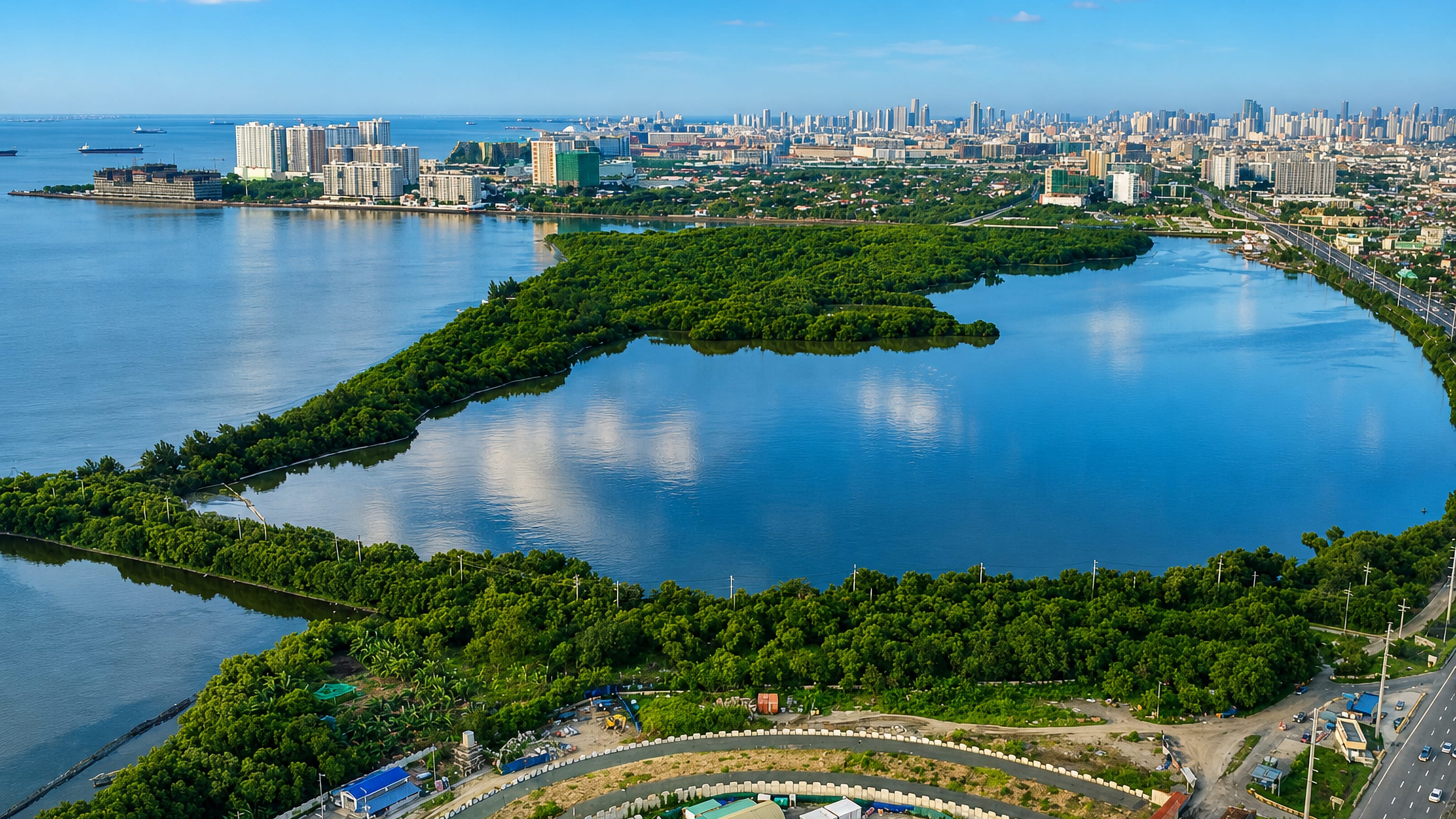 Aerial view over Parañaque City's mangrove wetlands and lagoons with Manila Bay and the skyline beyond.